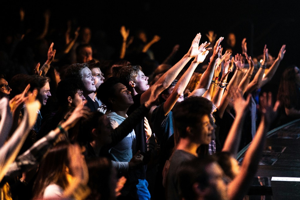 Students worshiping with hands raised — the fruit of hands-on ministry